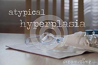 Words ATYPICAL HYPERPLASIA. Plastic vaginal speculum, pills and other tools in the background Stock Photo