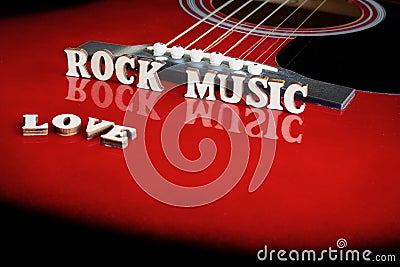 Words Love Rock Music with wooden letters, on reflecting surface of an acoustic guitar. Guitars bridge perspective. Creative Stock Photo