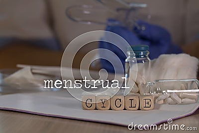 Words MENSTRUAL CYCLE composed of wooden dices. Pills, documents and a pen in the background Stock Photo