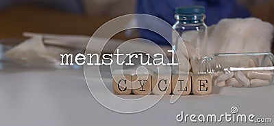 Words MENSTRUAL CYCLE composed of wooden dices. Pills, documents and a pen in the background Stock Photo