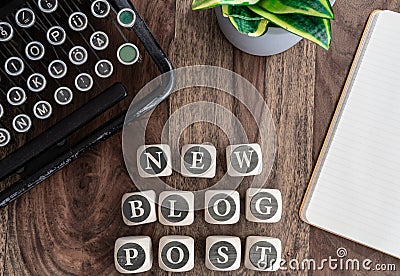Words NEW BLOG POST on wooden blocks on table with note pad, potted plant and vintage typewriter Stock Photo