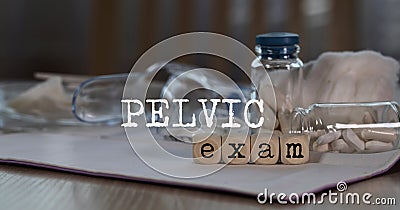 Words PELVIC EXAM composed of wooden dices. Pills, documents and a pen in the background Stock Photo