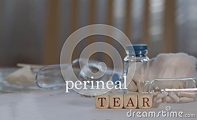 Words PERINEAL TEAR composed of wooden dices. Pills, documents and a pen in the background Stock Photo