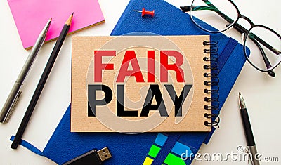 The words Play Fair in red text on a yellow sticky note on a green notice board as a reminder. Stock Photo