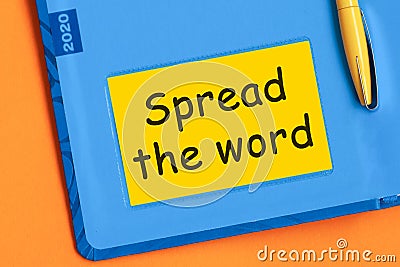 The words Spread the word is written in black letters on the yellow paper for notes Stock Photo