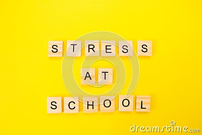 Words stress at school. Wooden blocks with an inscription on top on a yellow background. Social problems of teenagers and children Stock Photo