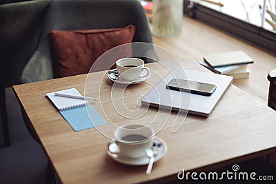 Work in cafe. Table with two white coffee cups and business stuff. Cozy place. laptop and smartphone Stock Photo