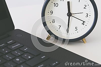 A work desk with a computer and office accessories and an alarm clock measuring the time running away. The concept of urgent deadl Stock Photo
