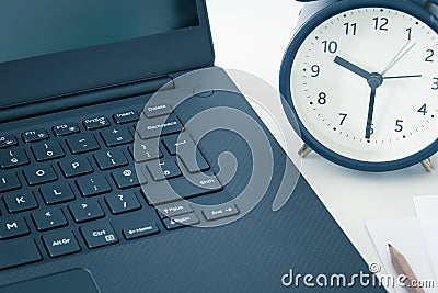A work desk with a computer and office accessories and an alarm clock measuring the time running away. The concept of urgent deadl Stock Photo