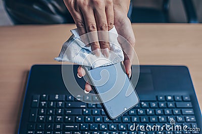 Work from home - cleaning and disinfecting smartphone and laptop computer with wet wipes Stock Photo