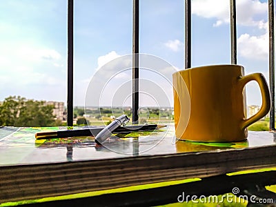 Work at home with coffee and tea cup pencil pen documents at balcony with blurred background sky and trees clear sunny weather Stock Photo