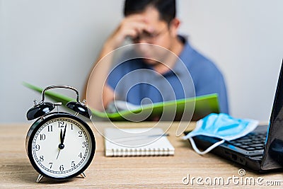 Work from home during the outbreak of the virus. Alarm Clock on the table at midnight with blur the businessman works from home Stock Photo