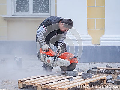 Work on laying the new tile on a city street. Lays the new tile on the floor. Paving in the city. Worker sawing the tiles. Russia. Editorial Stock Photo