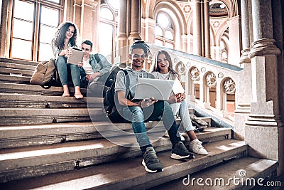 Work with the people that motivate and inspire you.Group of students studying while sitting on stairs in university Stock Photo