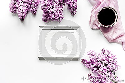 Work place with lilic flowers, coffee and frame for woman on white desk background top view mock-up Stock Photo