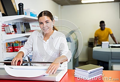 Work in printing house - woman cuts paper with professional cutter Stock Photo