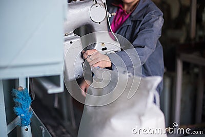 Work on the production of agricultural products. A Caucasian woman dressed in an iniform performs work on a conveyor that packs Editorial Stock Photo