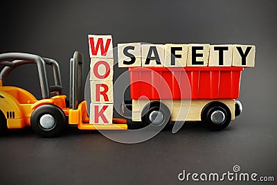 Work safety concept with wooden blocks on orange forklift with dark background Stock Photo