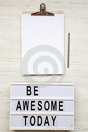 Work space with noticepad, pencil and `Be awesome today` word on lightbox over white wooden background, top view. From above, fl Stock Photo
