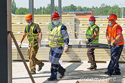 A work team carries a panel at the construction site of a medical aid and rescue center on a sunny summer day Editorial Stock Photo