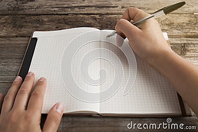 Work and time management, planning diary and human hand holding a pen close-up over opened note book. Rustic, old textured wooden Stock Photo