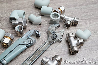 Plumbing concept set of piping accessories plumb adjustable wrenches fittings on wooden background. Plumbing tools and equipment Stock Photo