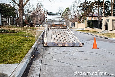 Work truck with tilting bed with machinery loaded and swirling track on pavement where a machine made sharp turn in upscale Stock Photo