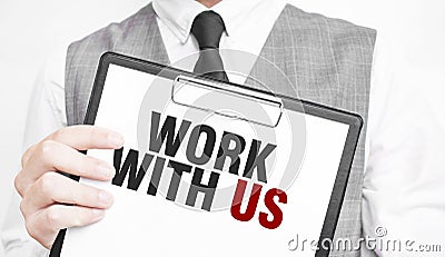 WORK WITH US inscription on a notebook in the hands of a businessman on a gray background, a man points with a finger to the text Stock Photo