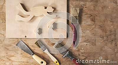 Workbench or desk carpenter with trowel, wood billets and brushes, art crafts diver and fish made from wood, copy space Stock Photo