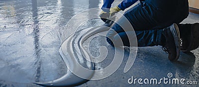 The worker applies gray epoxy resin to the new floor Stock Photo