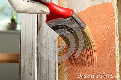 Worker applying coral paint onto wooden surface, closeup Editorial Stock Photo