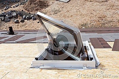 Worker on a asphalt shingle roof installing new plastic mansard or skylight window. Stock Photo