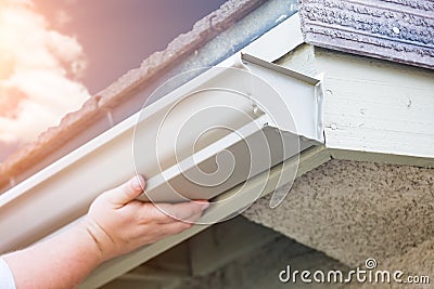 Worker Attaching Aluminum Rain Gutter to Fascia of House Stock Photo