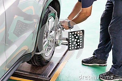 Worker attaching wheel alignment device equipment onto wheel car Stock Photo