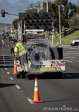 Worker behind utility truck placing bright orange traffic cones on roadway f Editorial Stock Photo