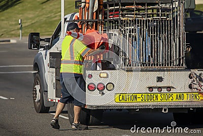 Worker behind utility truck placing bright orange traffic cones on roadway for traffic control Editorial Stock Photo