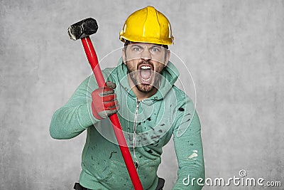 A worker with a big hammer screams like a possessed man Stock Photo