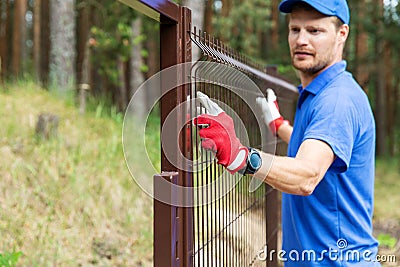 Worker installing welded metal mesh fence Stock Photo