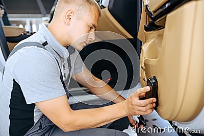 Worker with brush wipes car door trim, detailing Stock Photo
