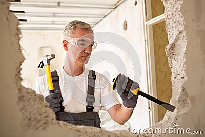 Worker builder demolish wall with tool Stock Photo
