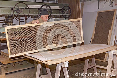 Worker in carpentry lines up glued wooden profiles before pressing in the large clamp machine Stock Photo