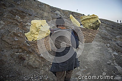 Worker carries sulfur inside Ijen crater in Ijen Volcano, Indonesia. Editorial Stock Photo