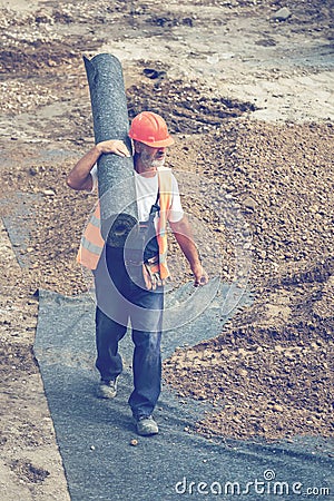 Worker carrying rolls of geotextile insulation 3 Editorial Stock Photo