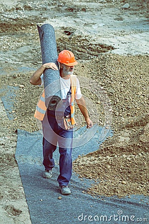 Worker carrying rolls of geotextile insulation 4 Editorial Stock Photo