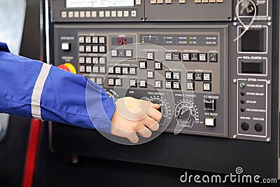 Worker changes feed override of CNC lathe machine Stock Photo