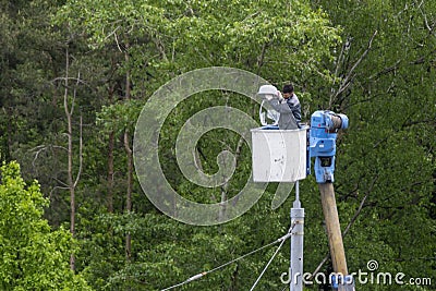 Worker changes a lamp in a street lamp Editorial Stock Photo