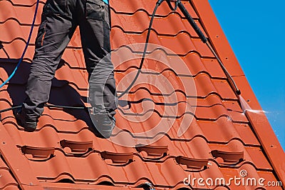 Worker cleaning metal roof with high pressure water Stock Photo