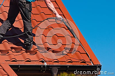 Worker cleaning metal roof with high pressure water Stock Photo