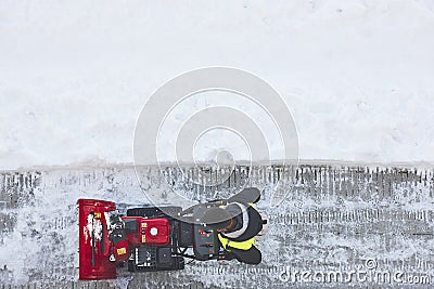 Worker cleaning snow on the sidewalk with a snowblower. Wintertime Editorial Stock Photo