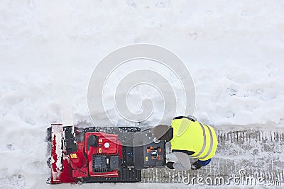 Worker cleaning snow on the sidewalk with a snowblower. Wintertime Editorial Stock Photo